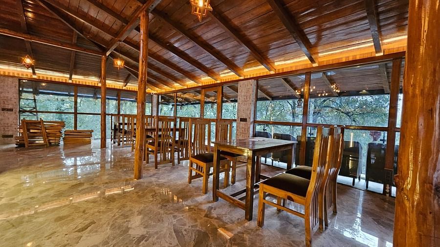 An image of the restaurant with wooden interiors featuring the chairs and tables - DLS The Emerald, Nainital